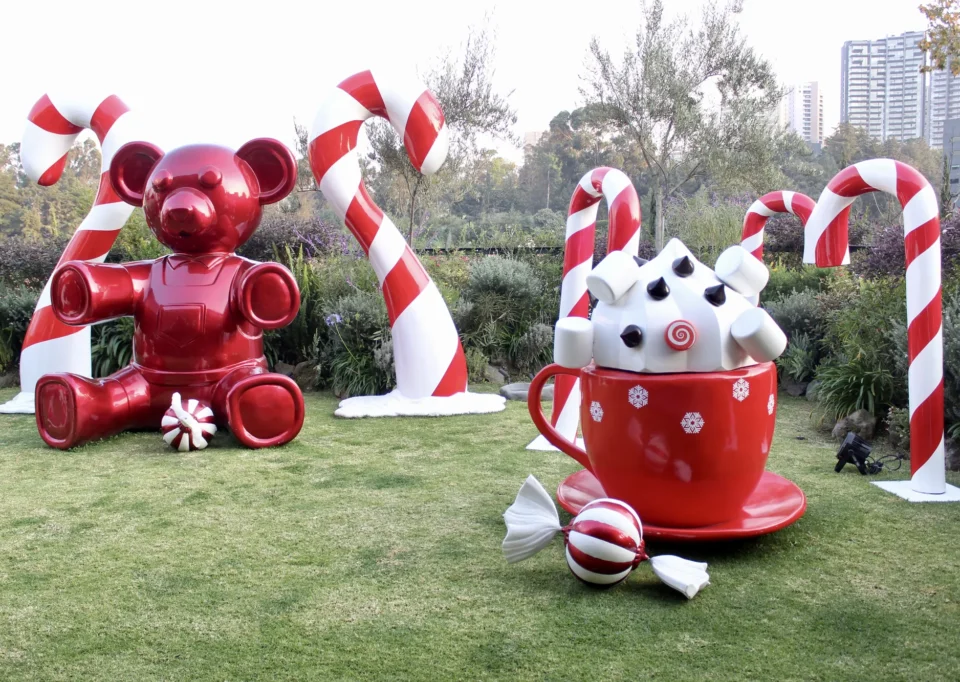 Jardín con oso rojo, taza gigante y bastones de caramelo