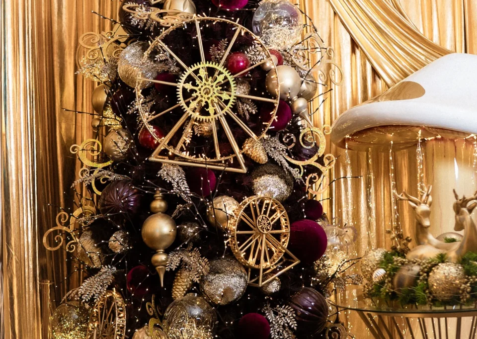 Árbol negro y dorado con ruedas de engranes frente a cortinas doradas