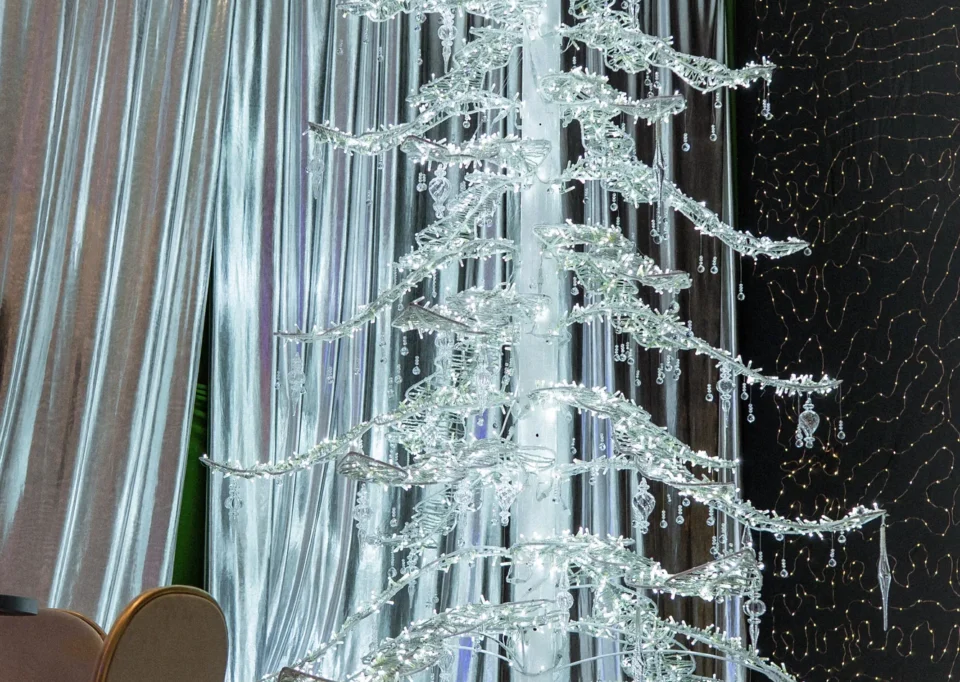Árbol de cristal iluminado frente a cortinas plateadas