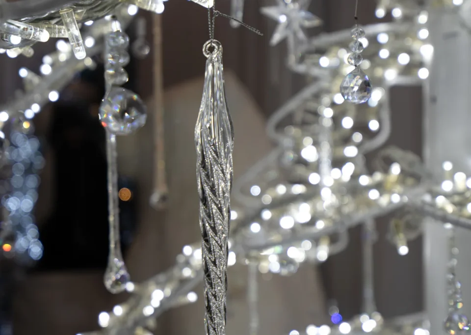 Detalle de un carámbano de cristal entre ramas plateadas iluminadas