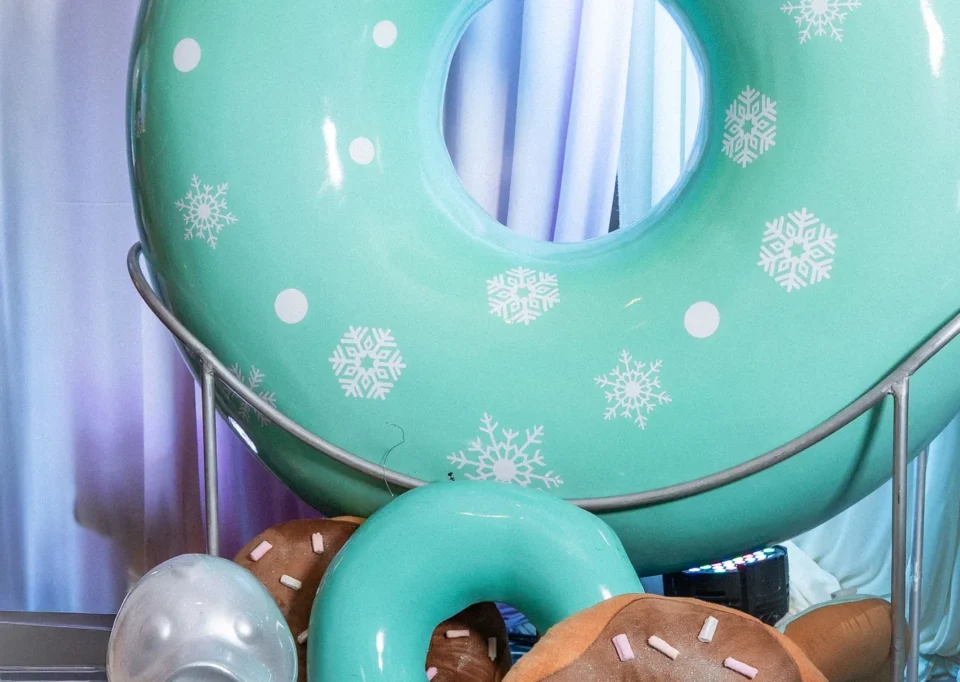 Dona gigante turquesa con donas de colores y pato plateado
