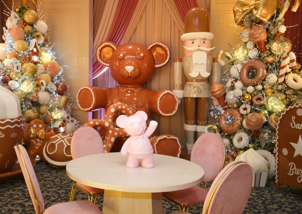 Oso de galleta gigante y mesa rosa entre árboles de dulces