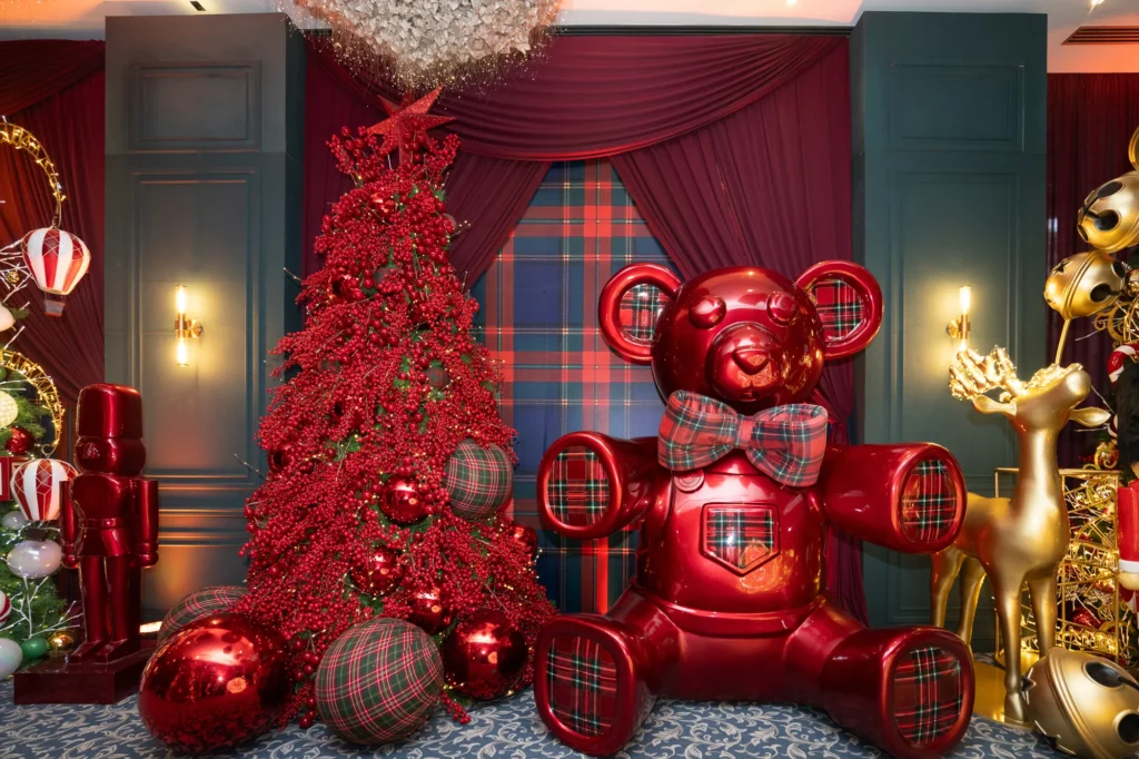 Showroom IM CHRISTMAS · Oso rojo de tartán junto a un árbol rojo Oso rojo de tartán junto a un árbol rojo
