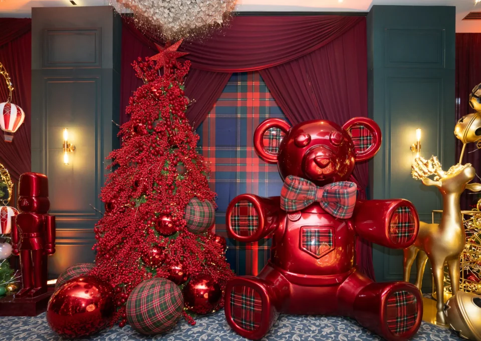 Oso rojo de tartán junto a un árbol rojo