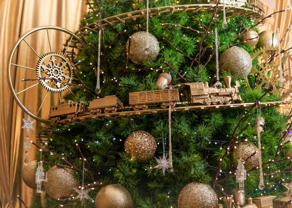 Tren dorado alrededor de un árbol navideño